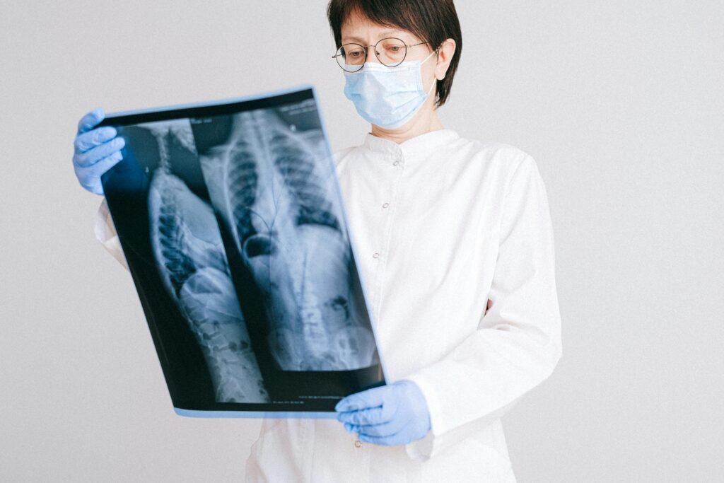 A doctor in protective gear analyzing an X-ray scan indoors.